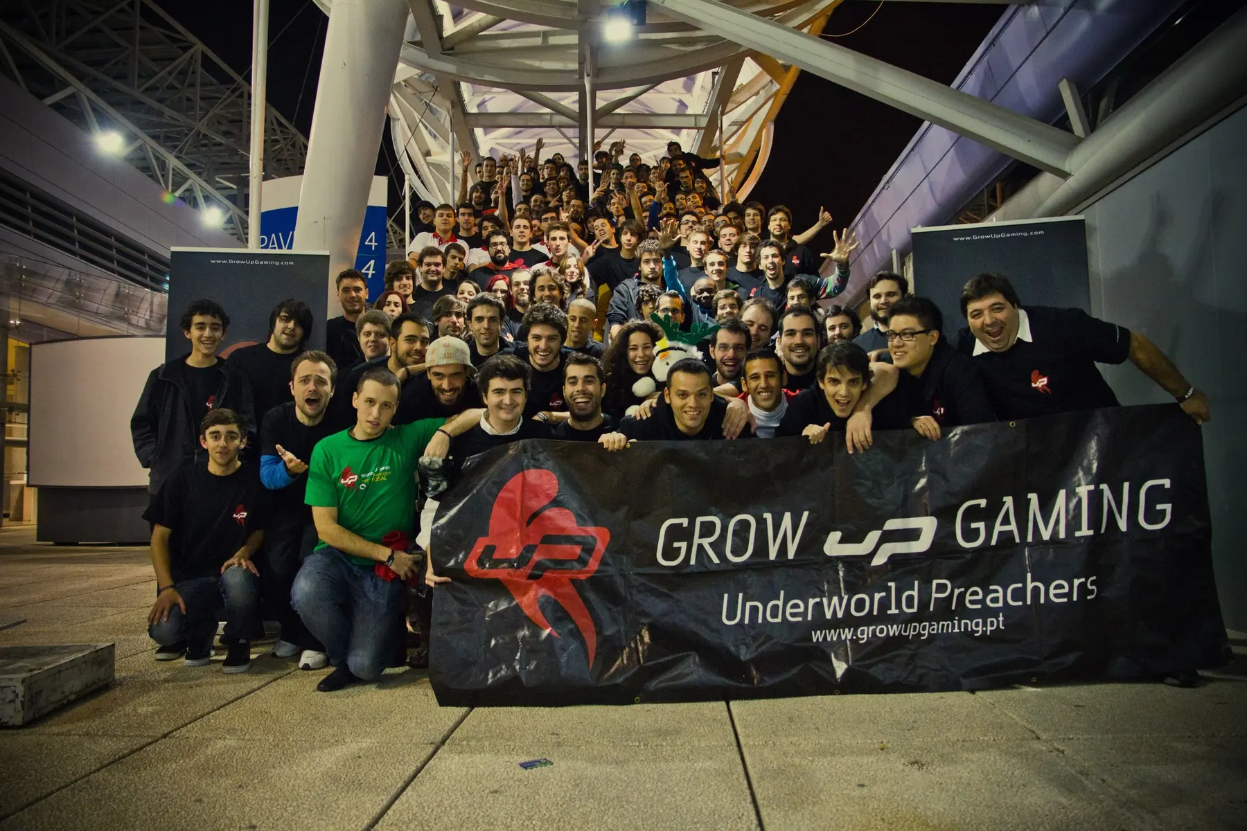 A large crowd of Grow uP Esports community members gathered behind a Grow uP Gaming and Underworld Preachers banner